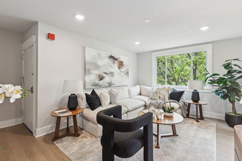 A living room with a white couch, a black chair, and a large painting on the wall.