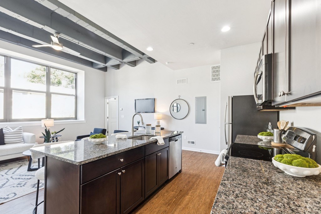A modern kitchen with dark wood cabinets and a granite countertop.