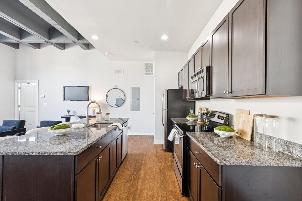 A modern kitchen with dark wood cabinets and granite countertops.