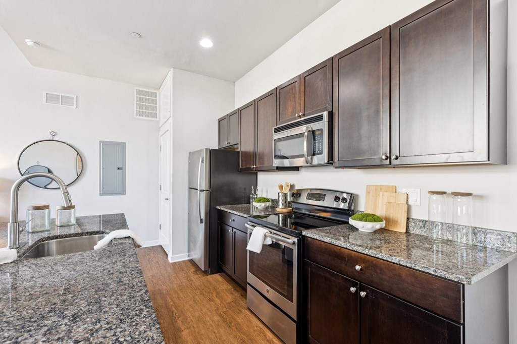 A kitchen with dark wood cabinets and a black fridge.