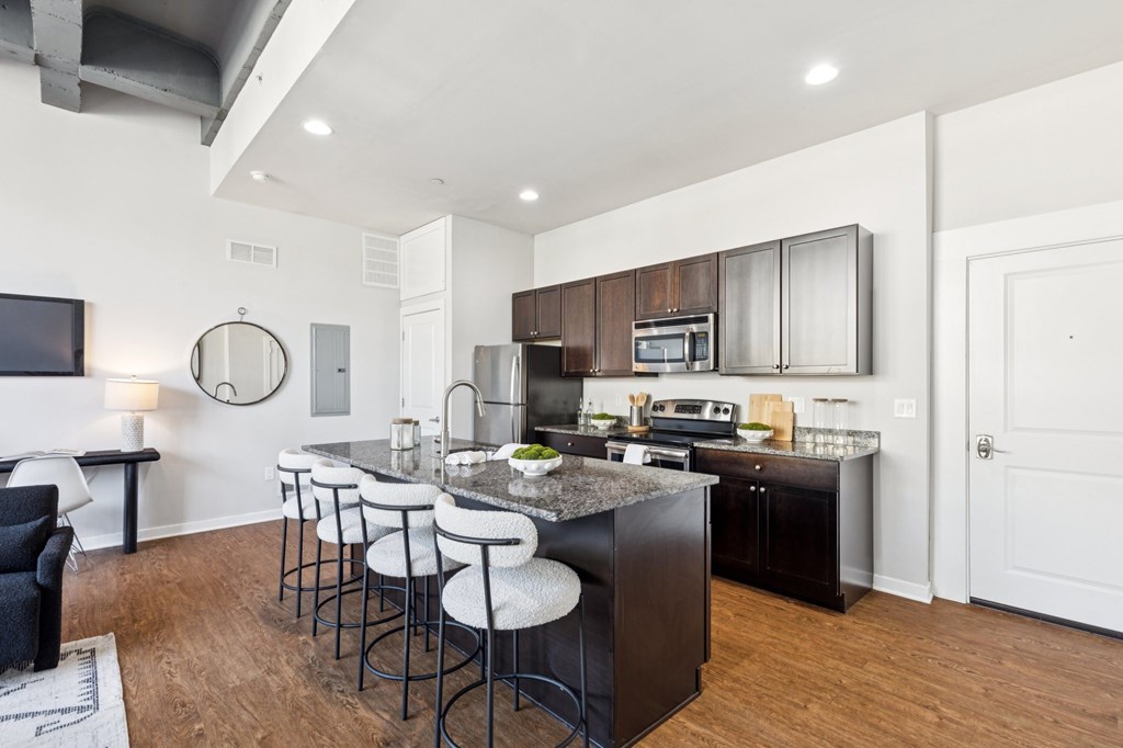 A kitchen with a bar area and a black chair.