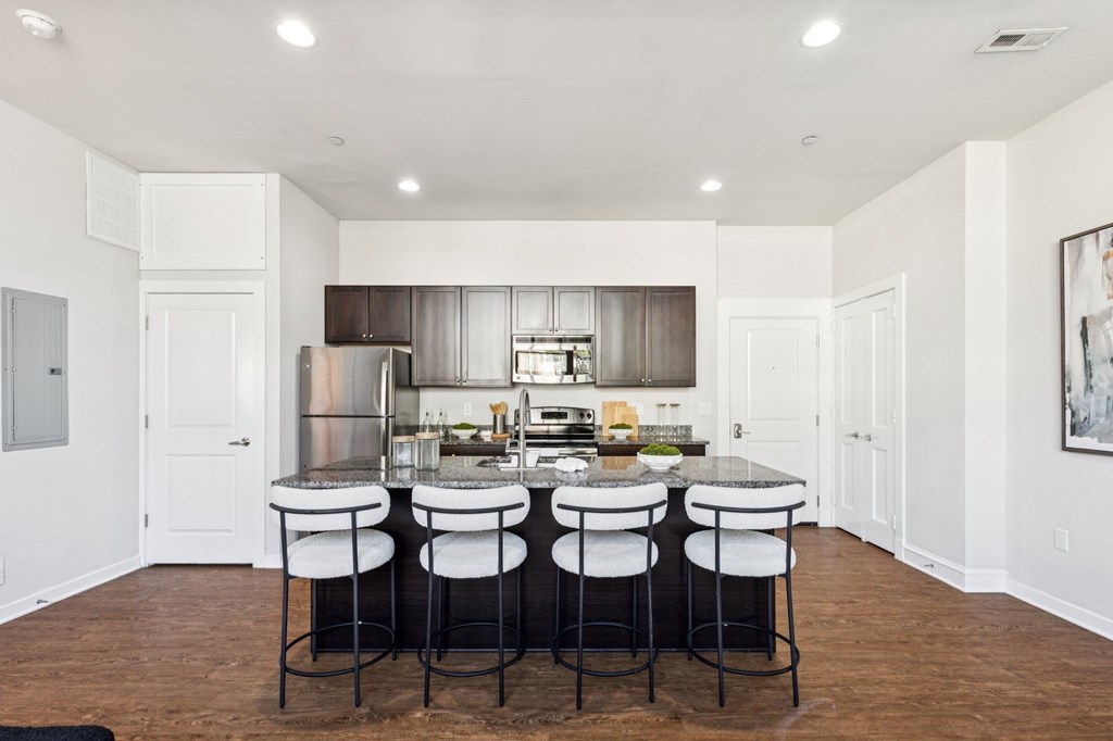 A kitchen with a bar and stools in the middle.