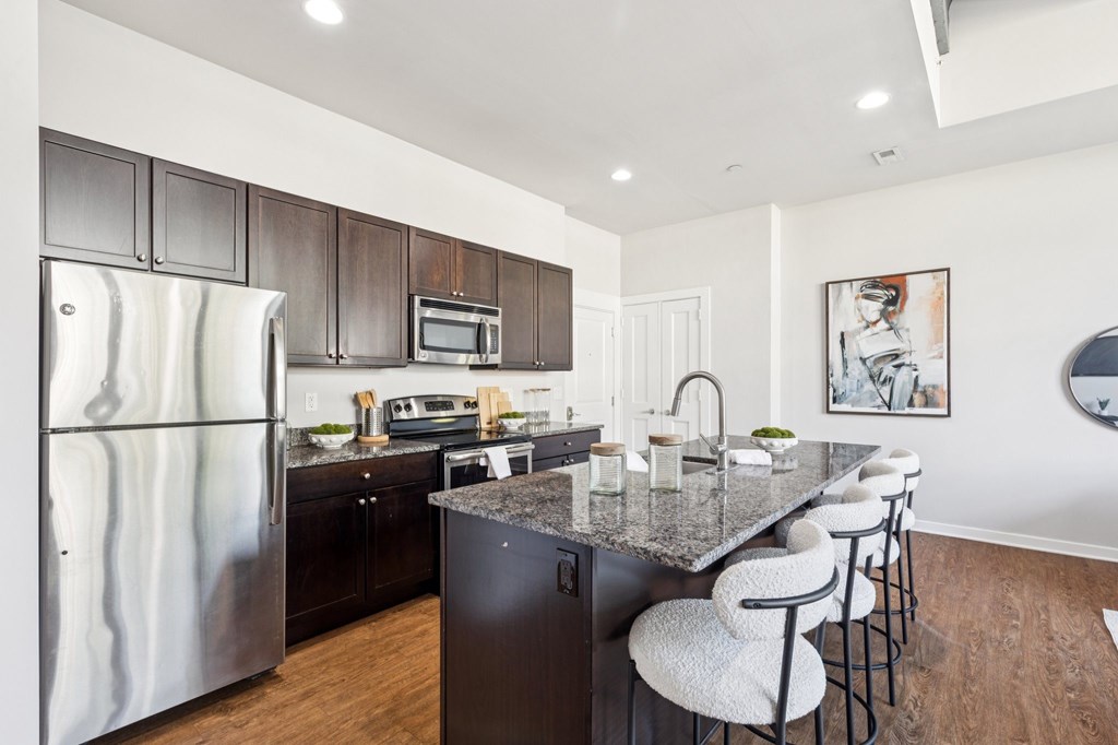A modern kitchen with a granite countertop and stainless steel appliances.