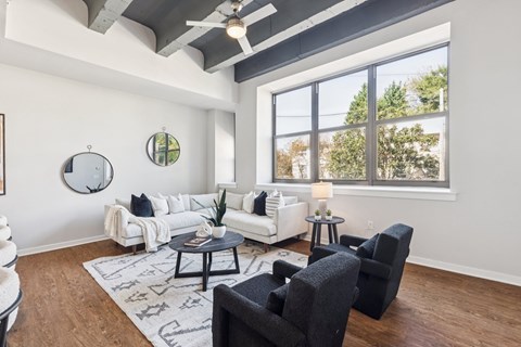 A living room with a white couch, a black chair, and a rug with a pattern on it.