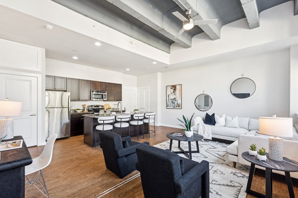 A modern living room with a kitchen in the background.