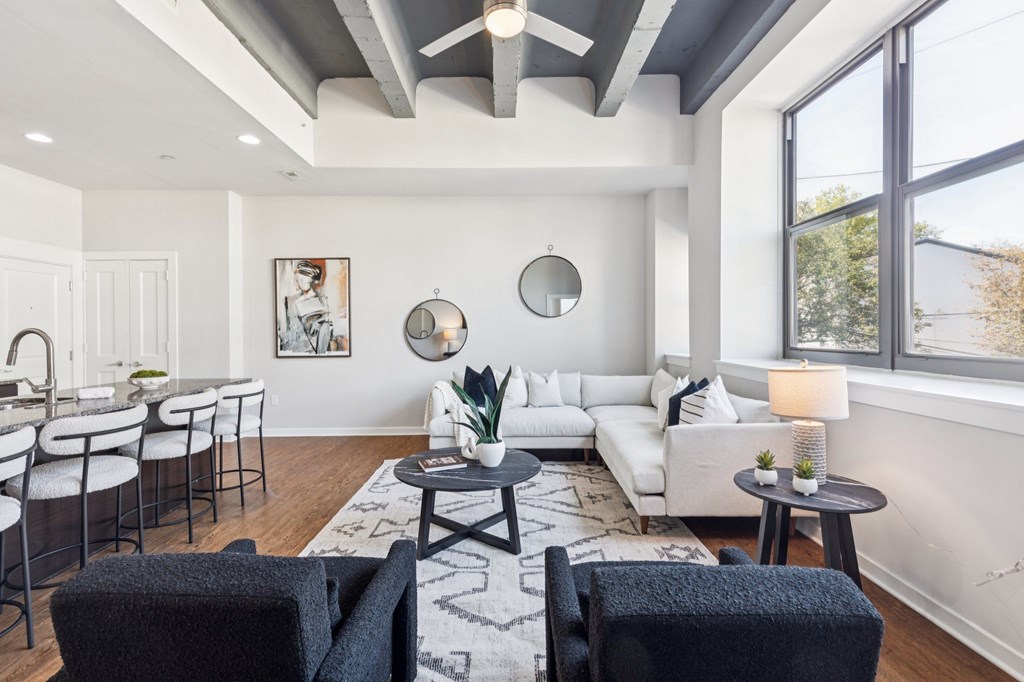 A modern living room with a white sofa, black chairs, and a rug.