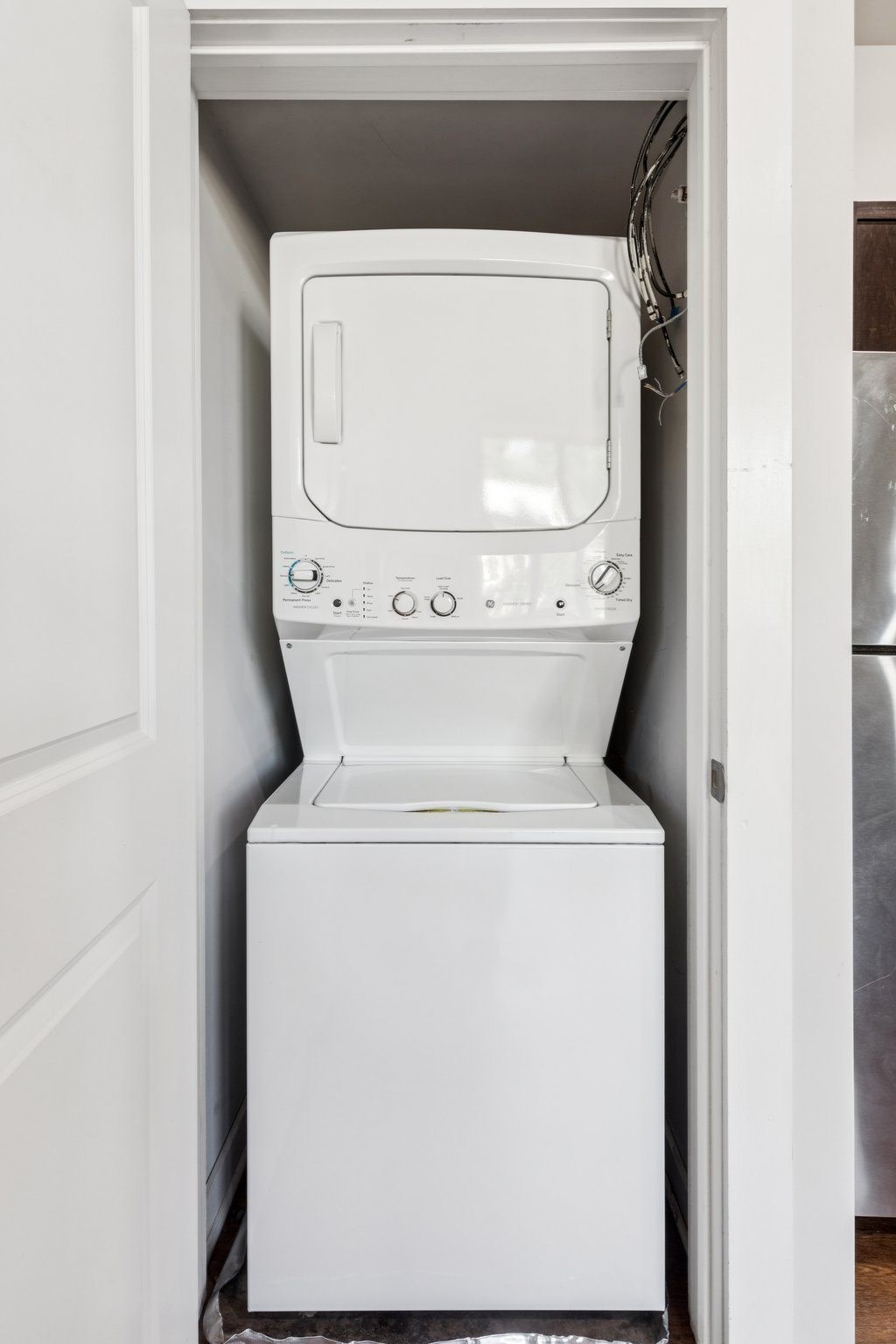 A white washing machine is sitting in a white door.