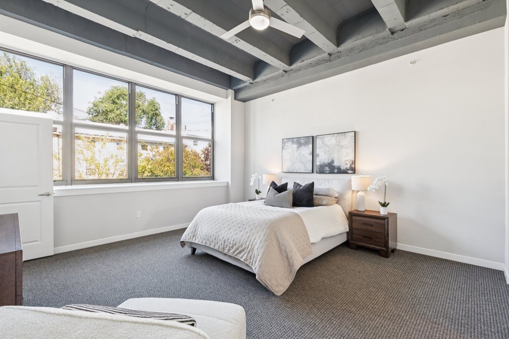 A bedroom with a large bed and a window overlooking trees.