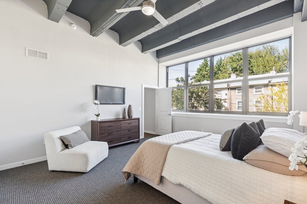 A bedroom with a large bed, a chair, and a television.