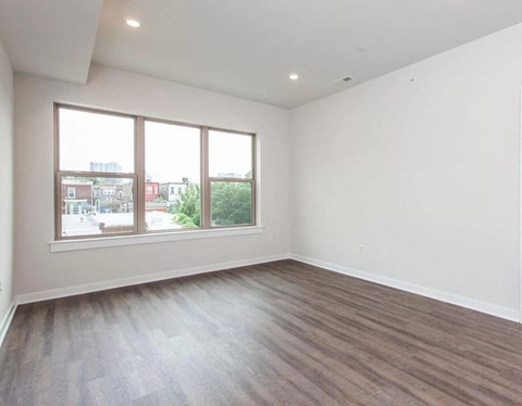 an empty living room with a large window and wooden floors