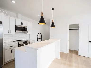 A kitchen with white cabinets and a white island.