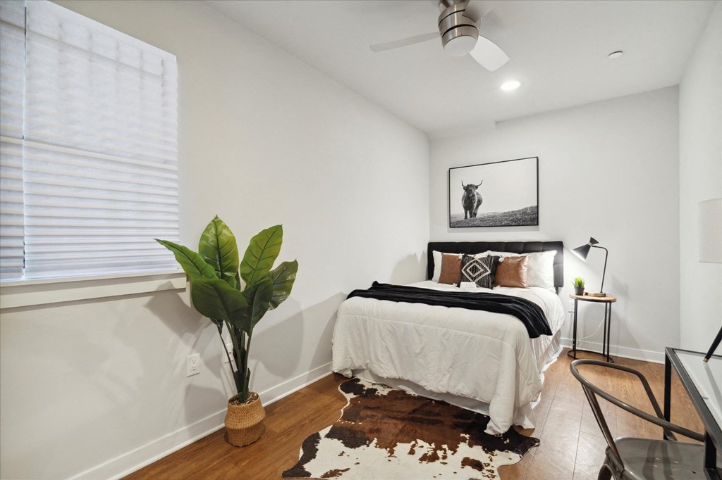 a bedroom with white walls and a bed with a black and white bedspread