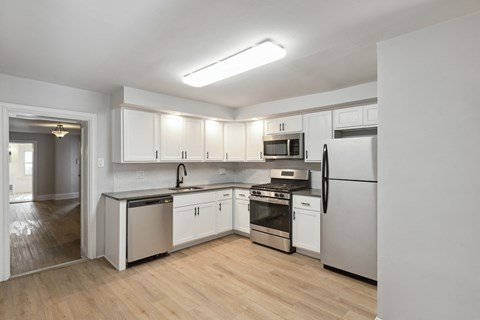 an empty kitchen with white cabinets and stainless steel appliances