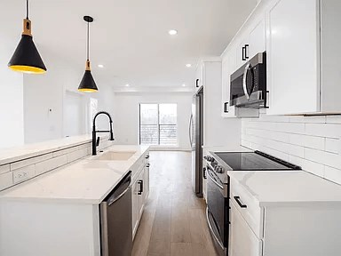 A modern kitchen with white cabinets and black appliances.