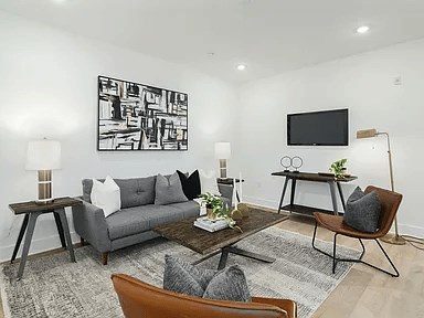 A living room with a grey couch, a coffee table, and a TV.