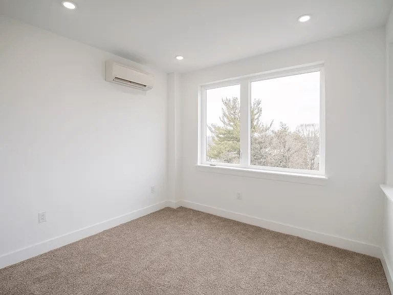 A room with a window and carpeted floor.