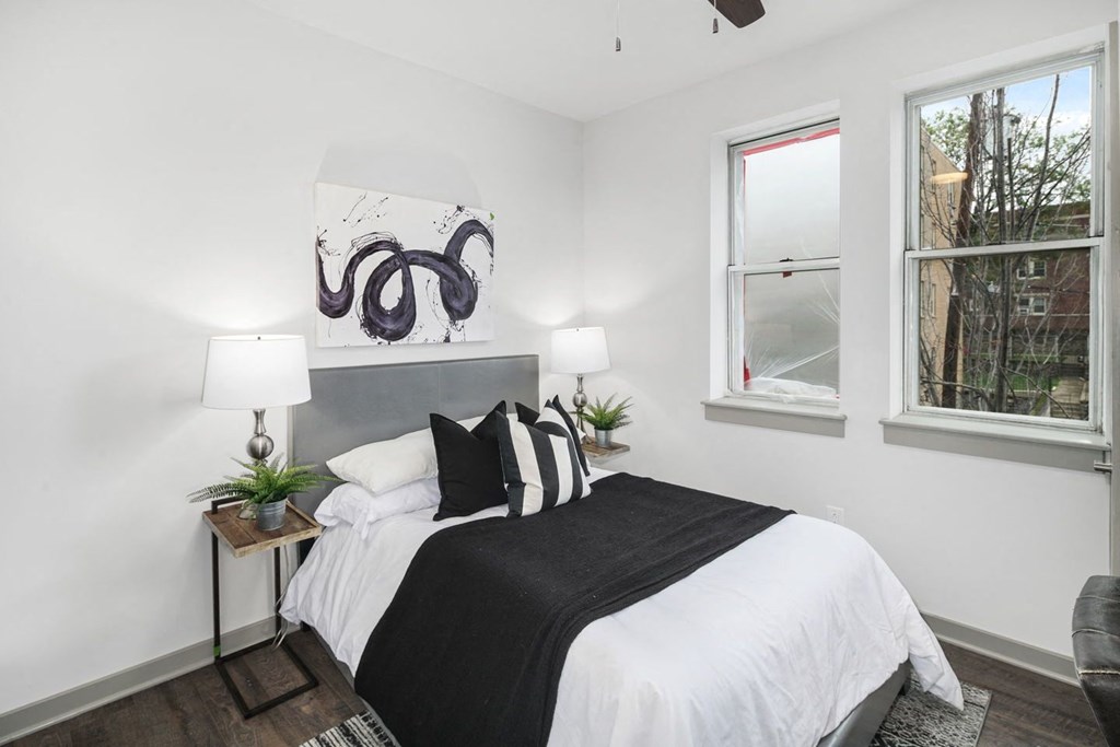 a bedroom with white walls and a white bed with black and white pillows