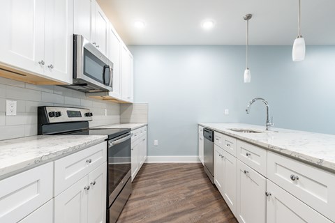 A kitchen with white cabinets and a marble countertop.