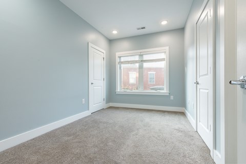 A room with a carpeted floor and a window showing a building outside.