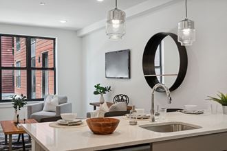 a kitchen and living room with white walls and a large window  at The Anchorage on Kelly, Philadelphia, PA - Photo Gallery 3