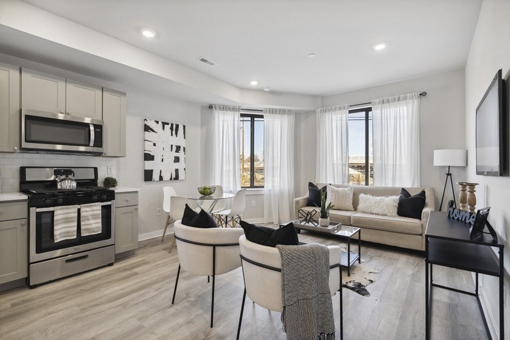 a living room and kitchen area with white walls and a wooden floor