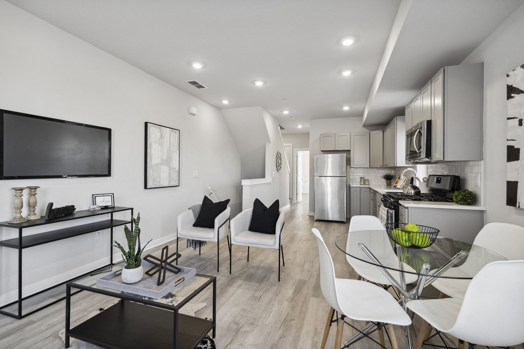 a living room and kitchen area with white walls and hardwood floors