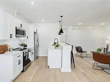 A modern kitchen with white cabinets and a wooden island.