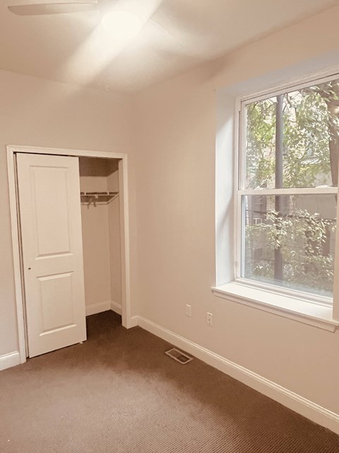 an empty bedroom with a window and a closet