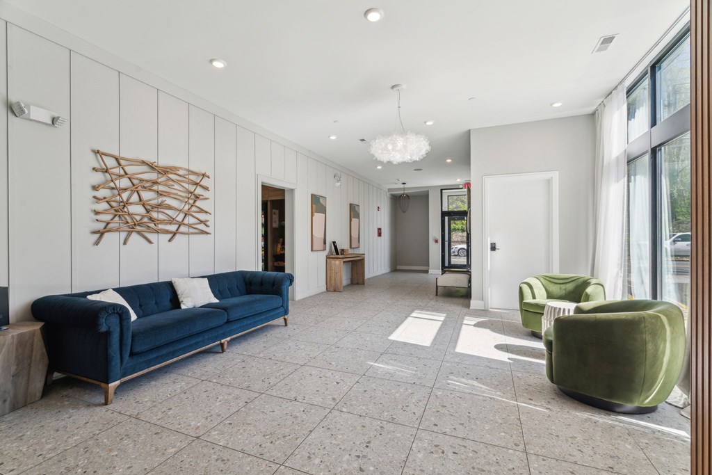 A spacious waiting area with a blue sofa, green armchair, and a wooden wall art.