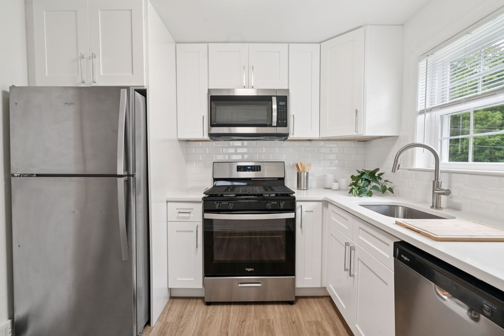 A modern kitchen with a refrigerator, microwave, oven, and sink.