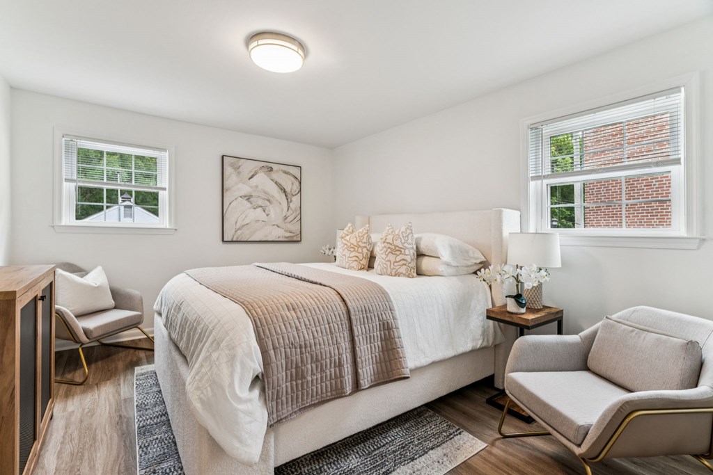A bedroom with a bed, chair, and window.