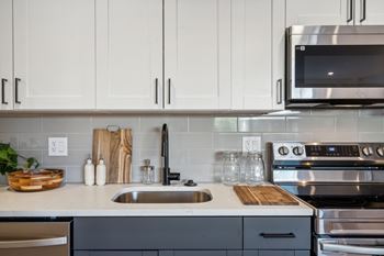 A modern kitchen with a stainless steel oven and white cabinets.