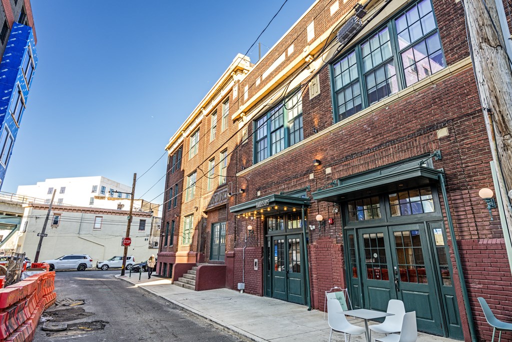 the front of a brick building with green doors and a sidewalk