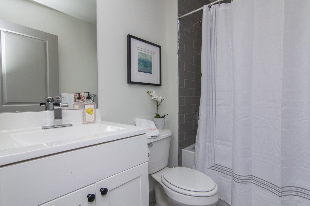 a bathroom with a white sink and toilet and a white shower curtain