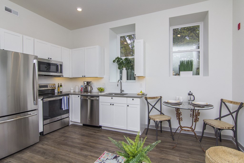 a kitchen with white cabinets and stainless steel appliances and a small table with two chairs