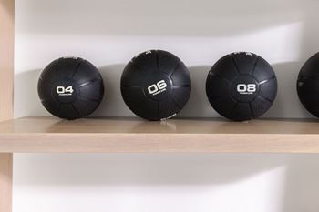 four black soccer balls sitting on a shelf