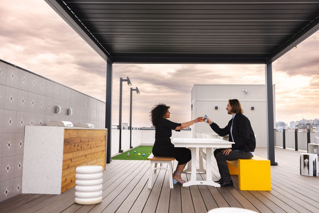 two women sitting at a table on a roof terrace shaking hands