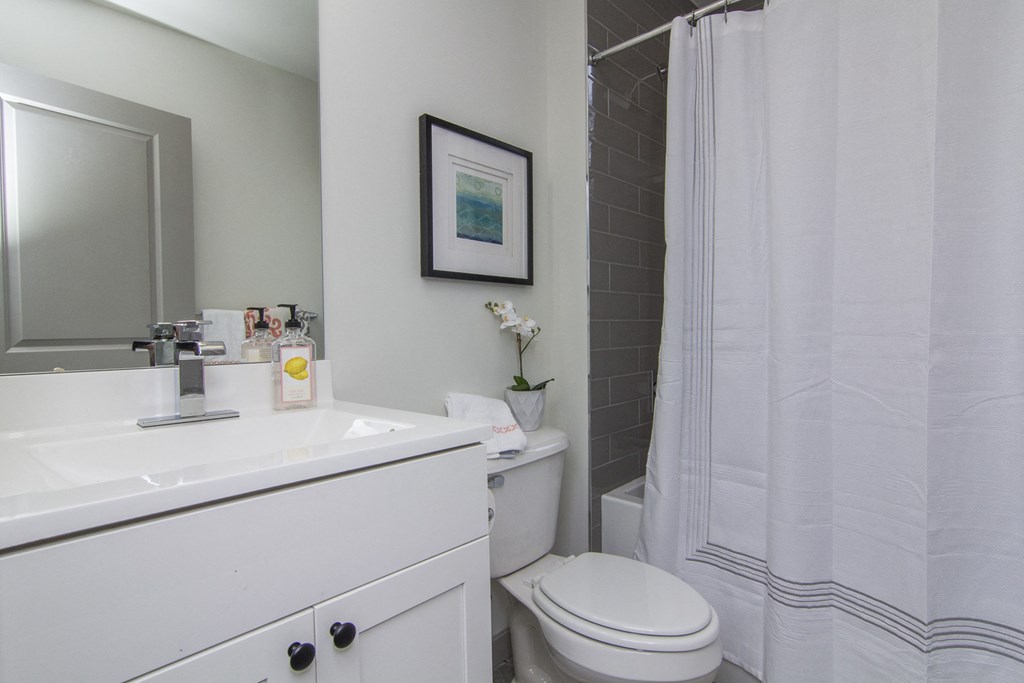 a bathroom with a white sink and toilet and a white shower curtain