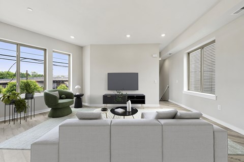 A modern living room with a grey sofa, a green armchair, a black coffee table, and a flat-screen TV.