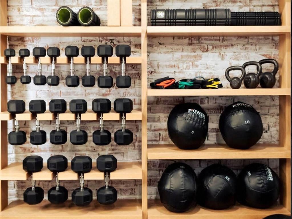 a collection of dumbbells sit on a wooden shelf