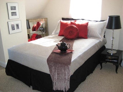 a bed with red pillows and a tea pot on it