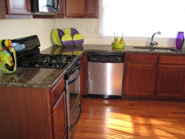 a kitchen with stainless steel appliances and wooden floors