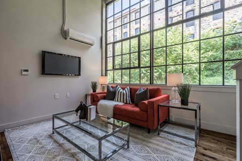 A living room with a red couch and a glass coffee table.