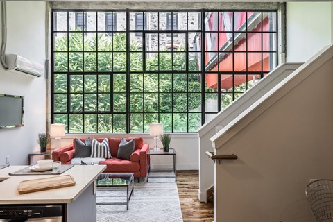 A living room with a red couch and a staircase.