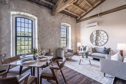 A dining room with a table set for two and a couch.