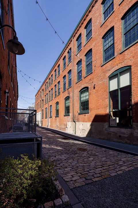 A brick building with green shutters and a metal gate.