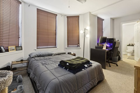 a bedroom with a bed and a desk and a bathroom