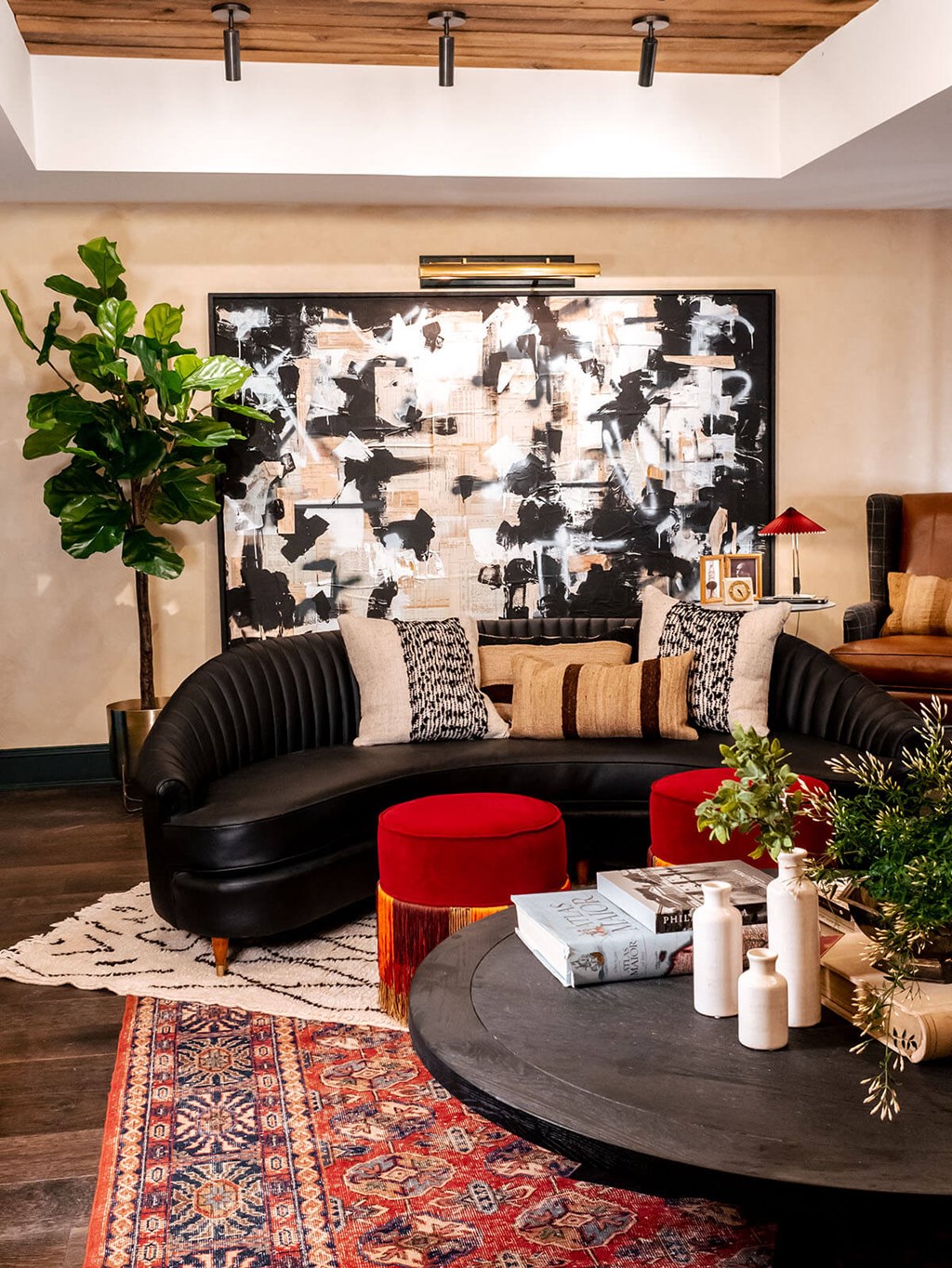 a living room with a black leather couch and red stools