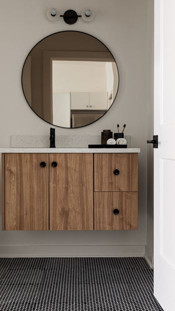 a bathroom with wooden cabinets and a round mirror