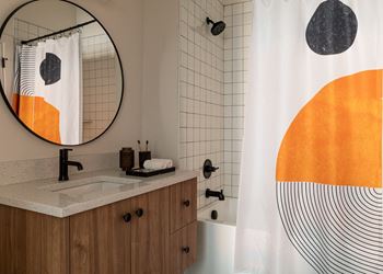 a bathroom with white walls and an orange and black shower curtain
